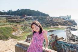 San Francisco Family Photography of Mixed Race Blended Little Girl in Red Floral Dress at Sutro Baths at Lands End Park with Bay Ocean Views