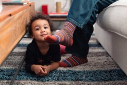San Francisco Family Photography of Young Mixed Race Blended Little Girl on Floor Next to Dad's Feet in Home