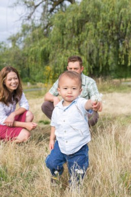 Seattle Family Photography of Adopted Baby Boy Sharing a Flower with Young Mom and Dad in Field
