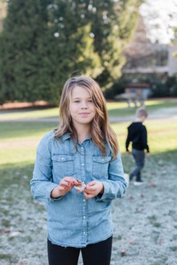 Young Girl in Jean Jacket with Frosted Leaf in Volunteer Park During Winter by Seattle Family Photographer